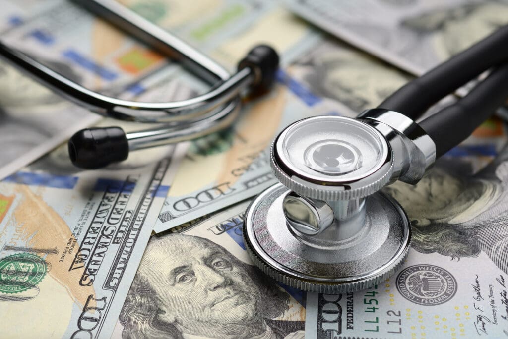 Medical stethoscope on heap of dollar bills. Health care or insurance costs concept. Finance banking audit analytics.