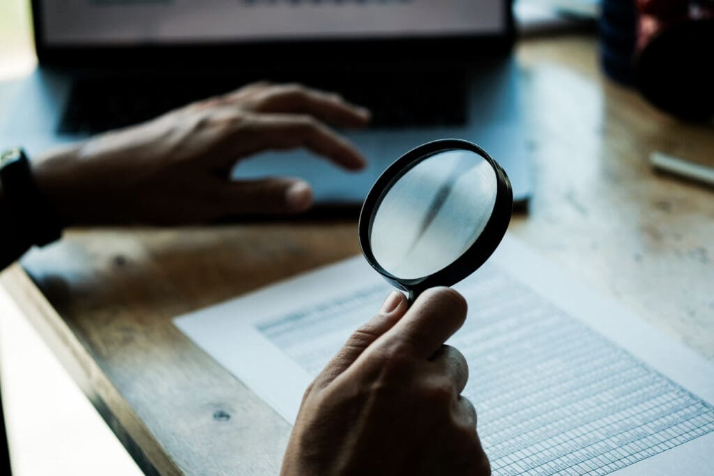 Businessman looking through a magnifying glass to documents. Business assessment and audit. Magnifying glass on a financial report. Close-up Of Businessperson Checking Bills With Magnifying Glass.Concept of search.
