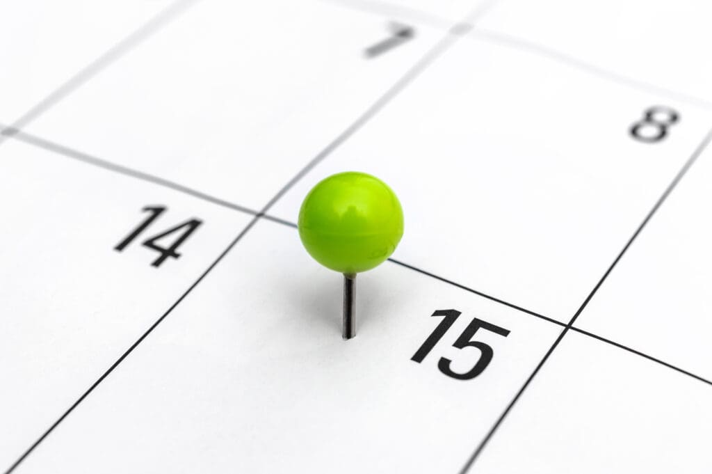 Green pinned pin in calendar on 15th day.