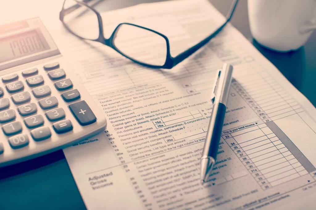 Individual income tax return form, glasses, pen and calculator on desk