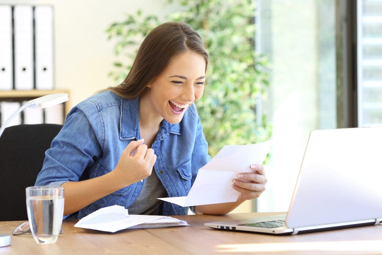 Excited casual entrepreneur girl reading good news in a letter in a desktop at office